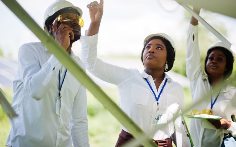 African american technician checks the maintenance of the solar panels. Group of three black engineers meeting at solar station.